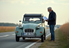 Véhicules exemptés contrôle technique : liste complète et réglementation en France Homme en jeans et veste consulte des papiers près d'une 2CV vintage en campagne