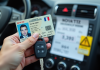 Permis de conduire et clé de voiture en main avec ticket en arrière-plan