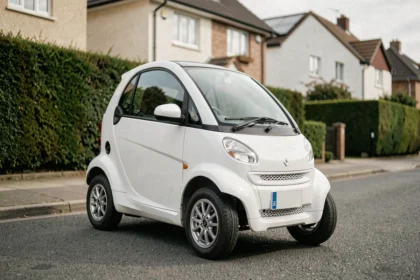 Petite voiture sans permis blanche garée dans une rue résidentielle calme, vue de trois quarts avant